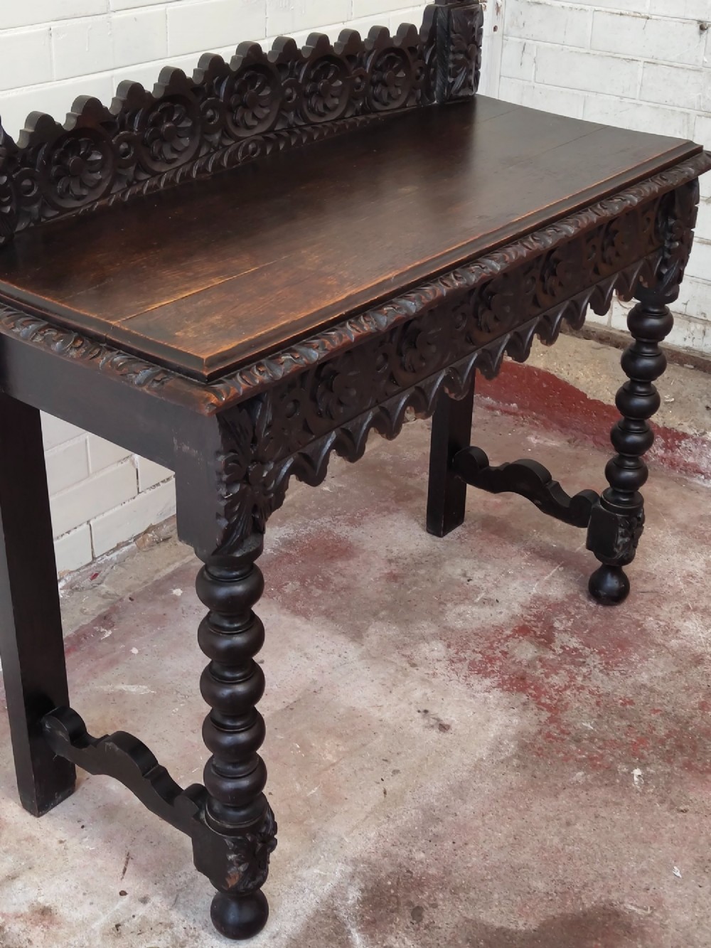 Dark carved oak hall table featuring a carved floral gallery, relief apron, bobbin-turned front legs, and lower stretcher. View XII