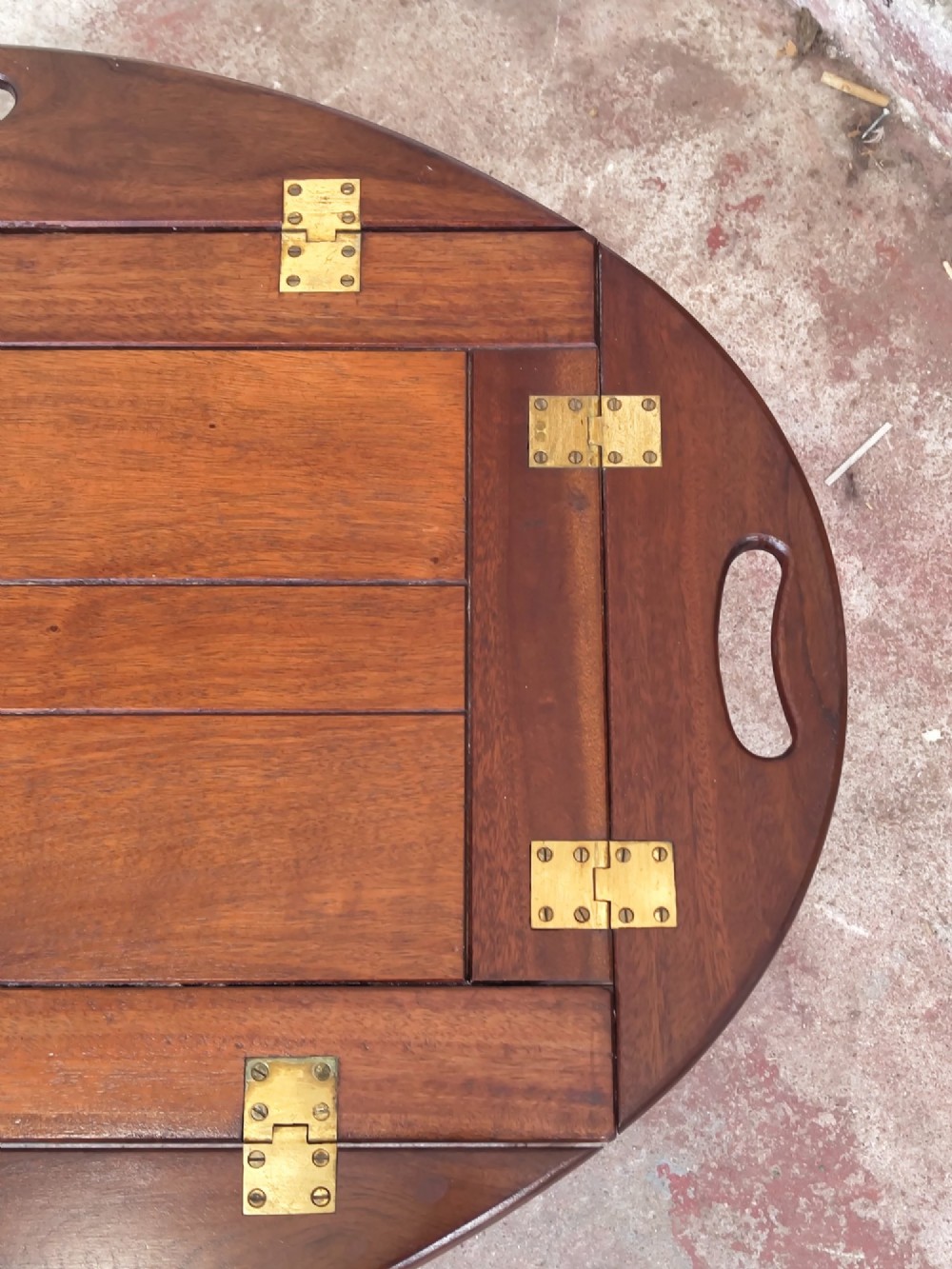 An antique mahogany butlers tray with hinged folding sides and brass fittings resting on a rectangular wooden stand. View VI