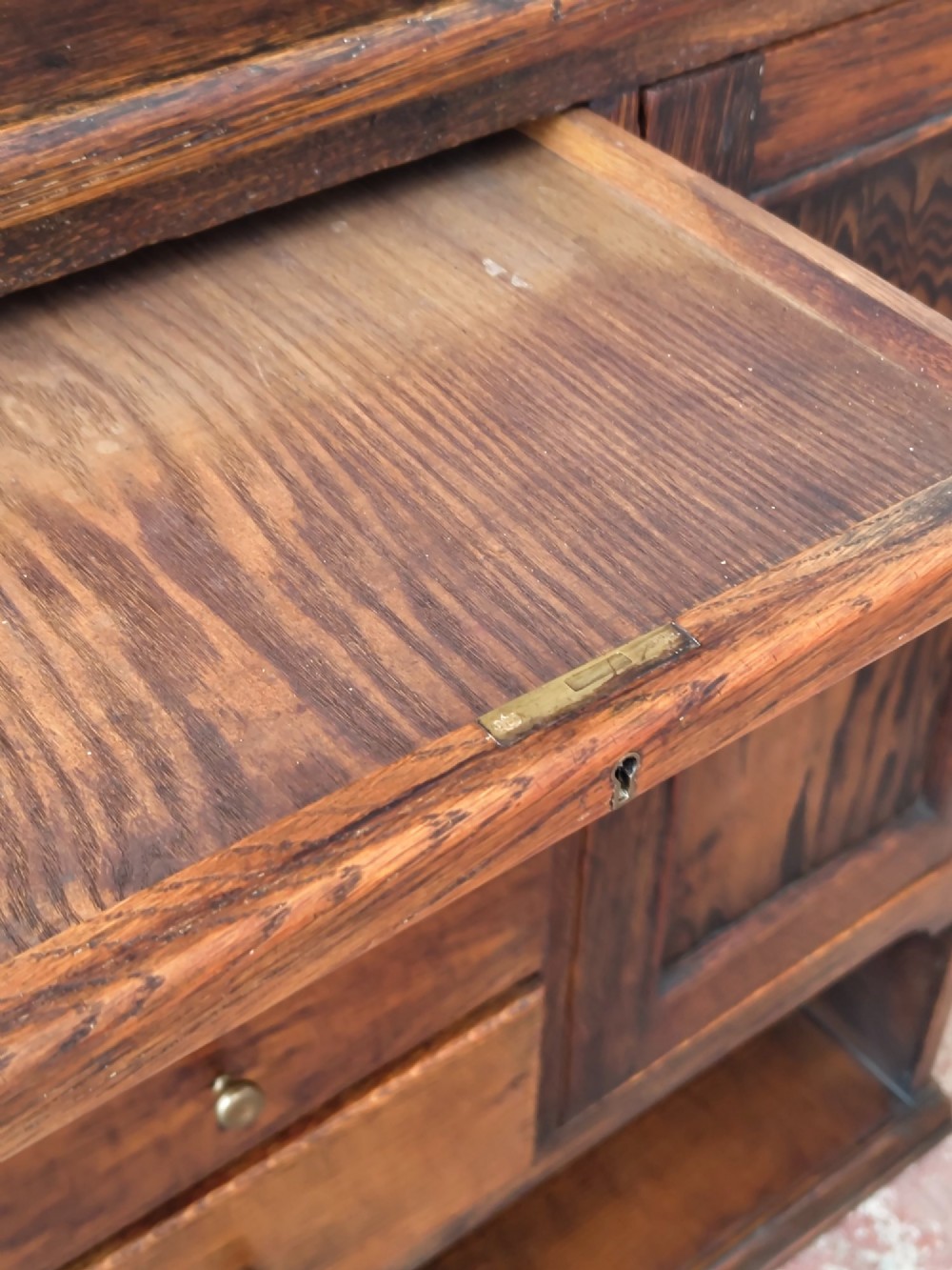 An Edwardian solid oak dentist cabinet featuring multiple shallow drawers, paneled cupboard doors, brass turned knobs, and an open lower shelf. View VIII