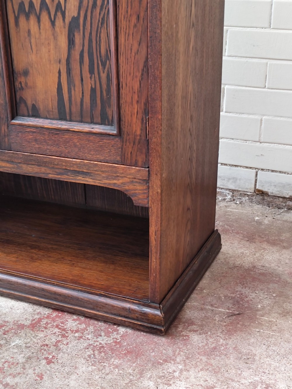 An Edwardian solid oak dentist cabinet featuring multiple shallow drawers, paneled cupboard doors, brass turned knobs, and an open lower shelf. View XIII