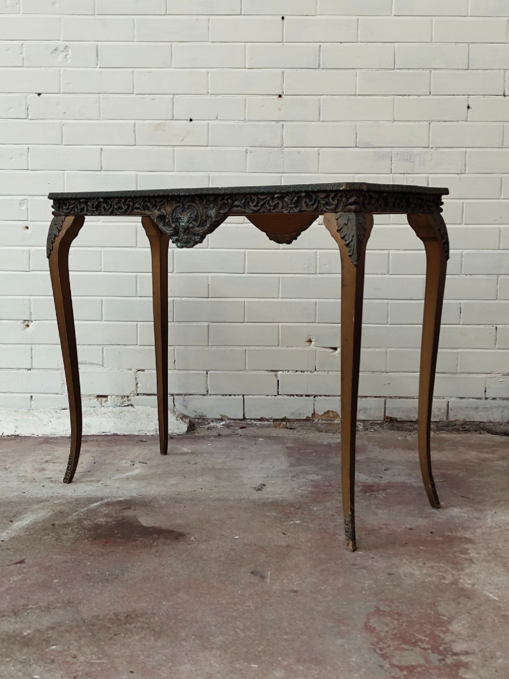 A diminutive French Rococo style console table featuring slender gilt cabriole legs, carved aprons, and a dark faux marble top. View III