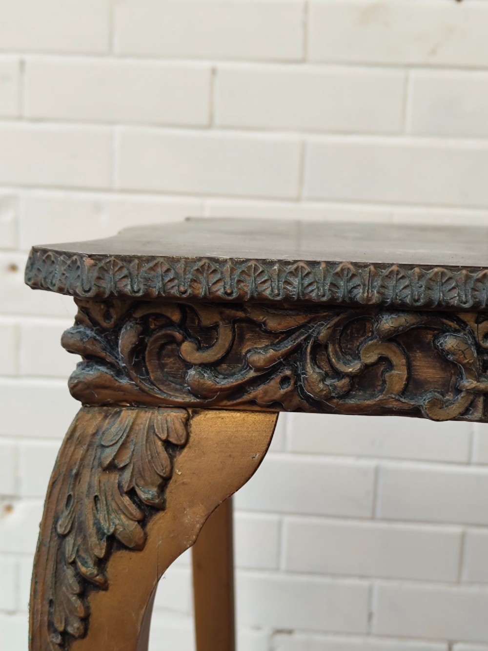 A diminutive French Rococo style console table featuring slender gilt cabriole legs, carved aprons, and a dark faux marble top. View VI