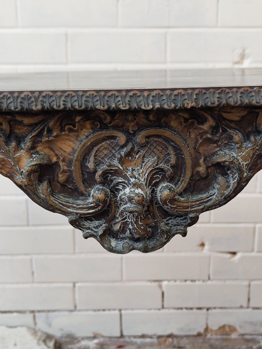 A diminutive French Rococo style console table featuring slender gilt cabriole legs, carved aprons, and a dark faux marble top. View VIII