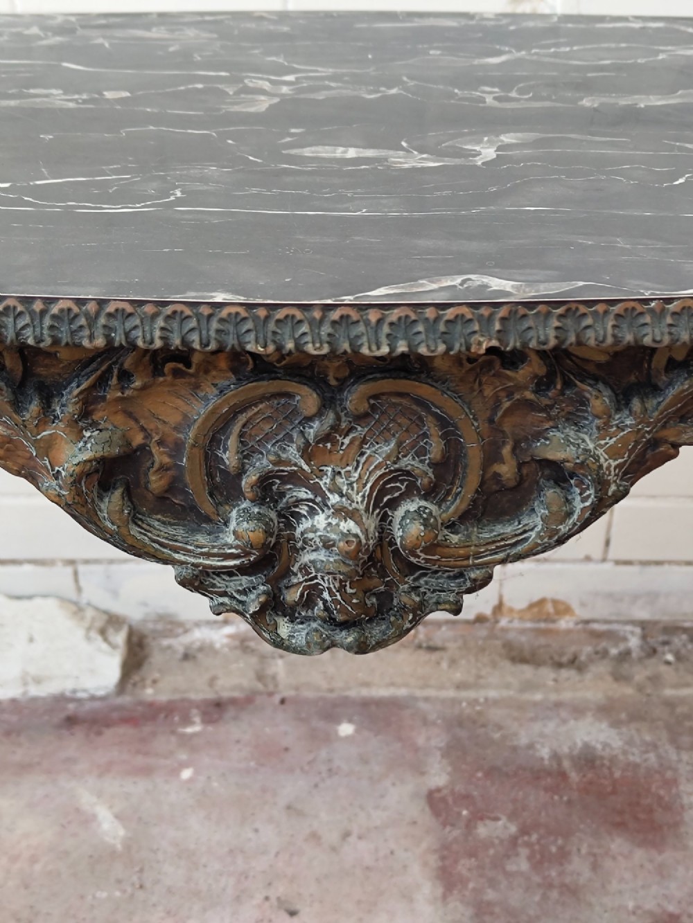 A diminutive French Rococo style console table featuring slender gilt cabriole legs, carved aprons, and a dark faux marble top. View IX
