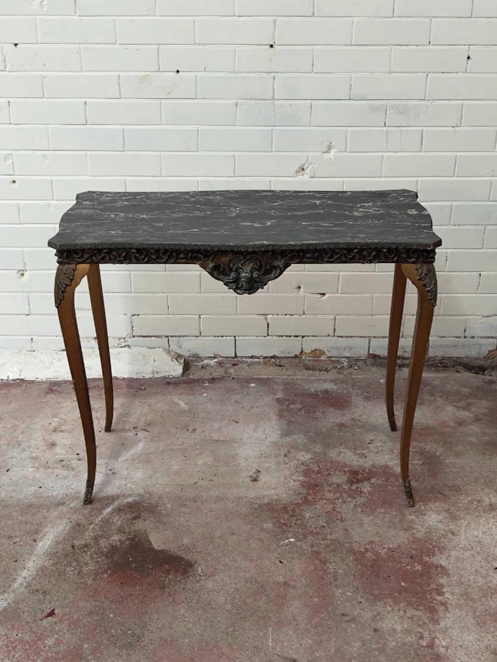 A diminutive French Rococo style console table featuring slender gilt cabriole legs, carved aprons, and a dark faux marble top. View XI