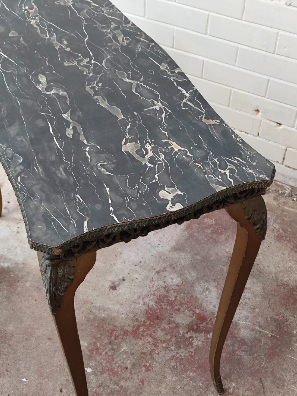 A diminutive French Rococo style console table featuring slender gilt cabriole legs, carved aprons, and a dark faux marble top. View XV