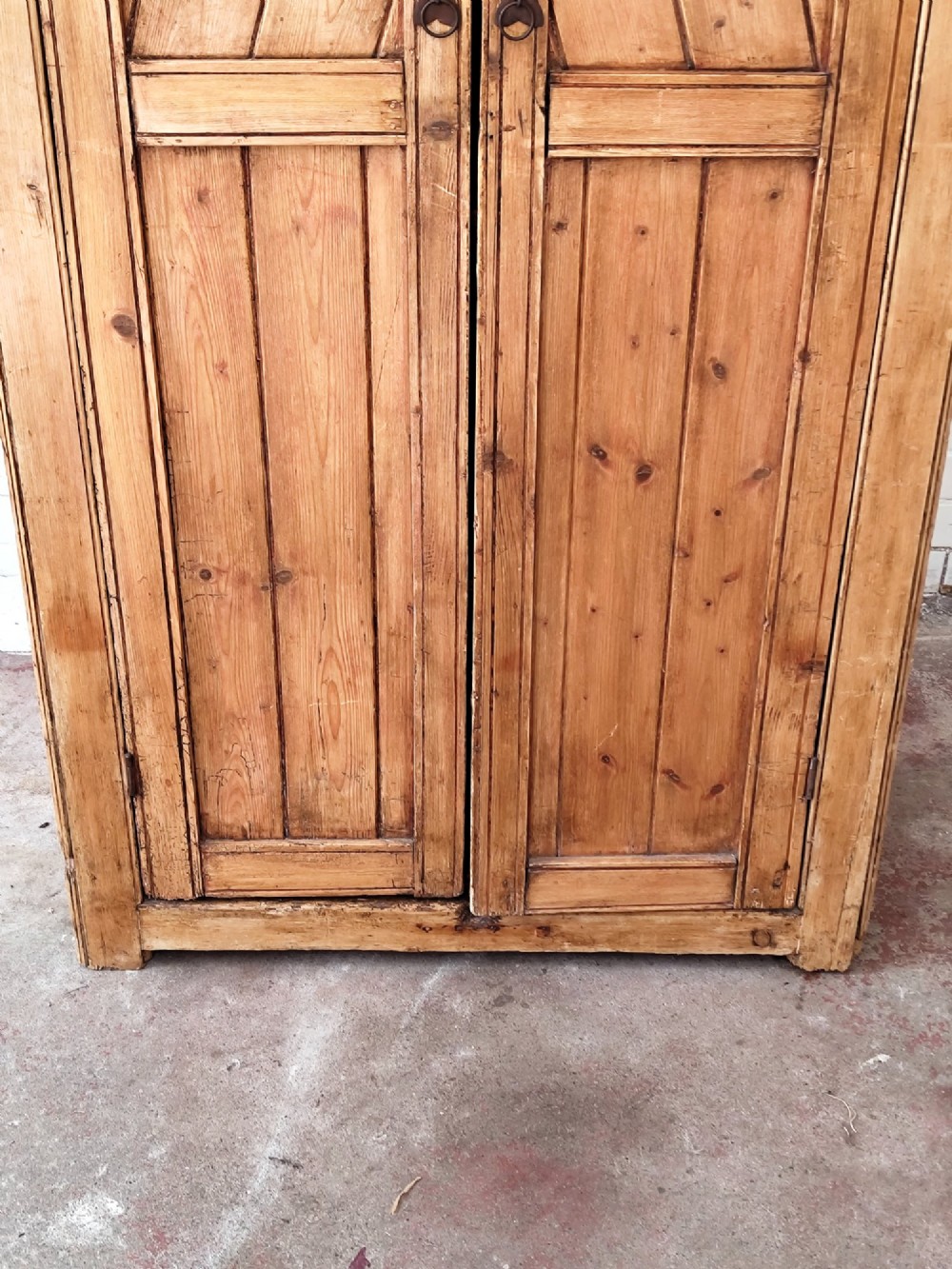 A tall antique pitch pine corner wardrobe featuring double doors with diagonal timber panels and a moulded top cornice. View III