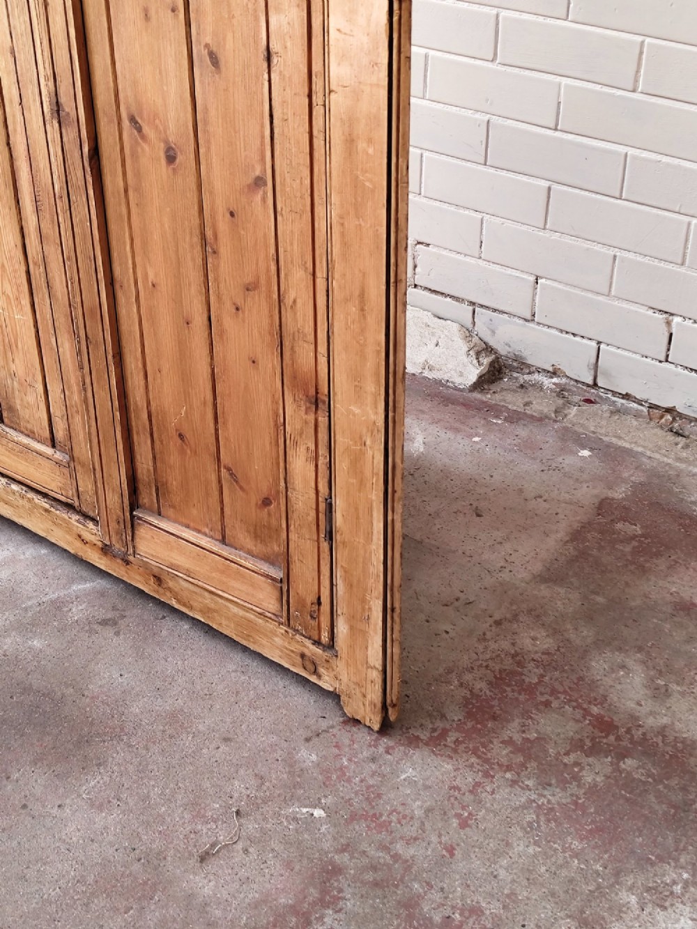A tall antique pitch pine corner wardrobe featuring double doors with diagonal timber panels and a moulded top cornice. View VI