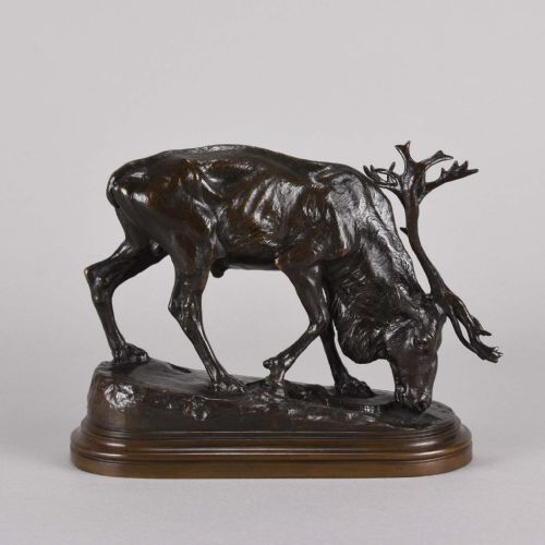 fig 1. A 19th-century dark brown patinated bronze sculpture depicting a grazing reindeer with branching antlers on an oval naturalistic base.