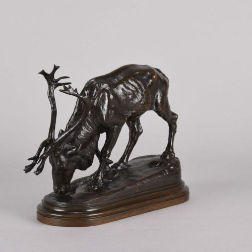 fig 3. A 19th-century dark brown patinated bronze sculpture depicting a grazing reindeer with branching antlers on an oval naturalistic base.