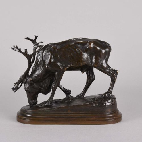 fig 4. A 19th-century dark brown patinated bronze sculpture depicting a grazing reindeer with branching antlers on an oval naturalistic base.