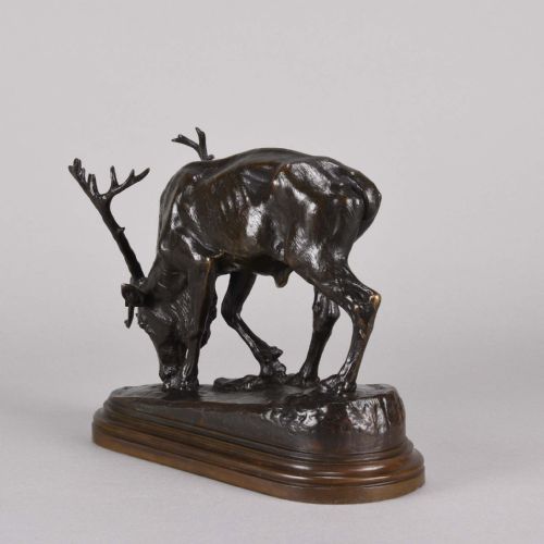 fig 5. A 19th-century dark brown patinated bronze sculpture depicting a grazing reindeer with branching antlers on an oval naturalistic base.