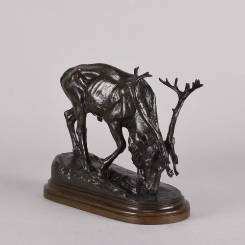 fig 6. A 19th-century dark brown patinated bronze sculpture depicting a grazing reindeer with branching antlers on an oval naturalistic base.