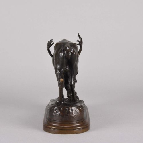 fig 7. A 19th-century dark brown patinated bronze sculpture depicting a grazing reindeer with branching antlers on an oval naturalistic base.