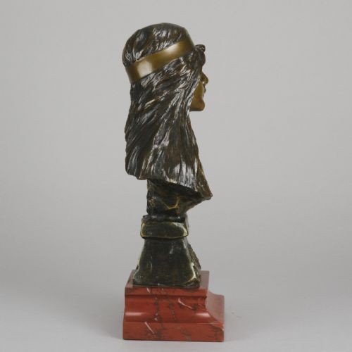 fig 2. An Art Nouveau patinated bronze bust of a young woman with long hair and a headband mounted on a red marble base.