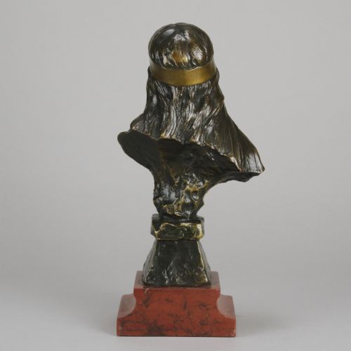 fig 4. An Art Nouveau patinated bronze bust of a young woman with long hair and a headband mounted on a red marble base.