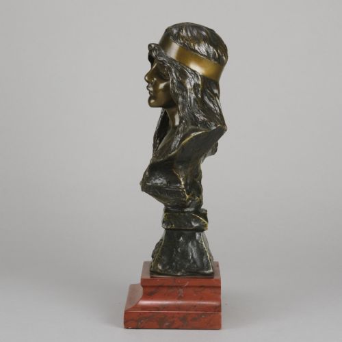 fig 5. An Art Nouveau patinated bronze bust of a young woman with long hair and a headband mounted on a red marble base.