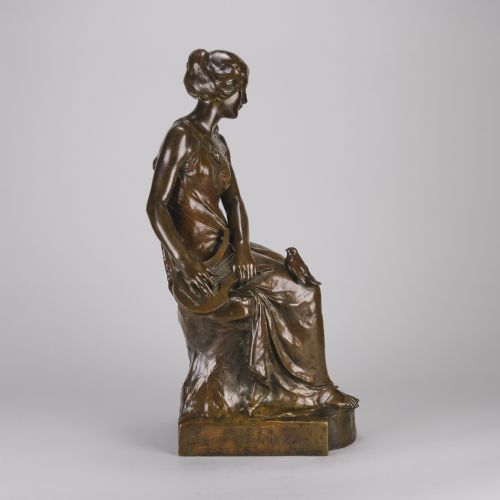fig 2. A dark brown patinated bronze sculpture depicting a seated woman in classical draped attire interacting with small birds, set on an integral bronze base.