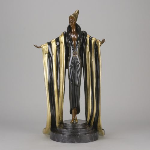 fig 2. An Art Deco cold-painted bronze figurine depicting a female figure in a floor-length black and gold robe standing on a stepped dark base.