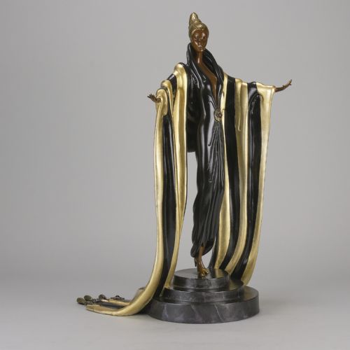 fig 3. An Art Deco cold-painted bronze figurine depicting a female figure in a floor-length black and gold robe standing on a stepped dark base.