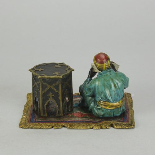 fig 5. A Viennese cold-painted bronze sculpture depicting a seated scholar in a turquoise robe writing beside an octagonal Moorish table on a patterned carpet.