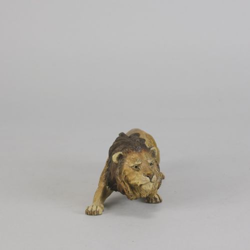fig 3. An early 20th-century cold-painted bronze figurine depicting a crouching lion with a dark brown mane and ochre coat.