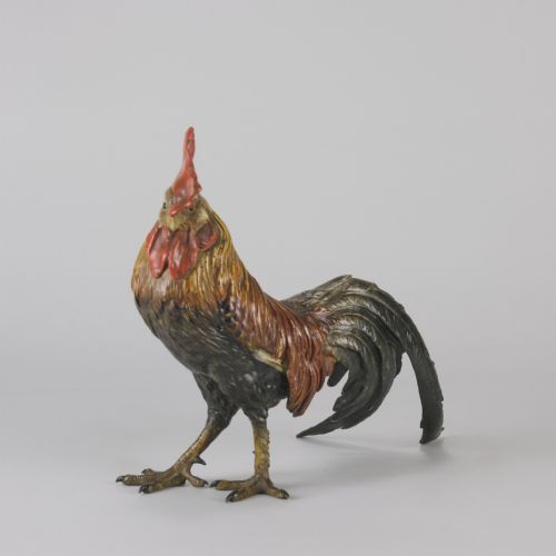fig 2. A cold-painted bronze figurine depicting a standing cockerel with a red comb and textured feathers in brown, ochre, and dark grey shades.