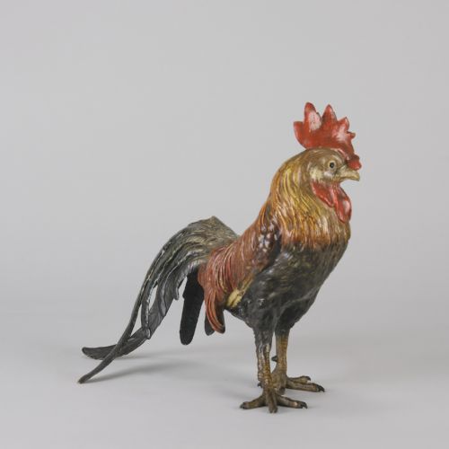 fig 3. A cold-painted bronze figurine depicting a standing cockerel with a red comb and textured feathers in brown, ochre, and dark grey shades.