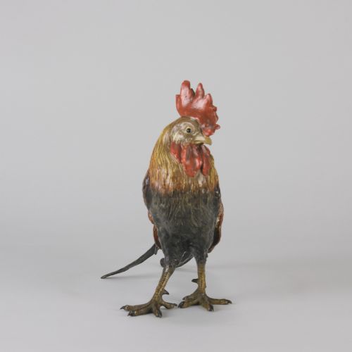 fig 5. A cold-painted bronze figurine depicting a standing cockerel with a red comb and textured feathers in brown, ochre, and dark grey shades.