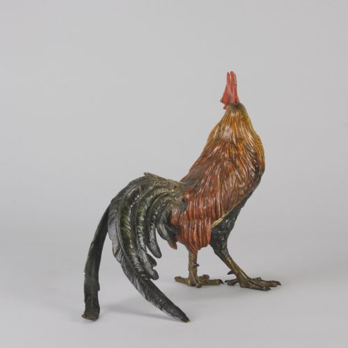 fig 6. A cold-painted bronze figurine depicting a standing cockerel with a red comb and textured feathers in brown, ochre, and dark grey shades.