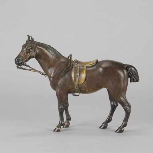 fig 1. A cold-painted bronze sculpture depicting a saddled horse with gold-coloured tack, bridle, and stirrups in a standing pose.