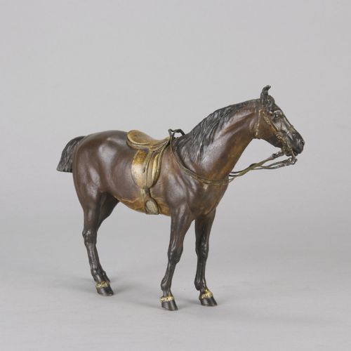 fig 2. A cold-painted bronze sculpture depicting a saddled horse with gold-coloured tack, bridle, and stirrups in a standing pose.