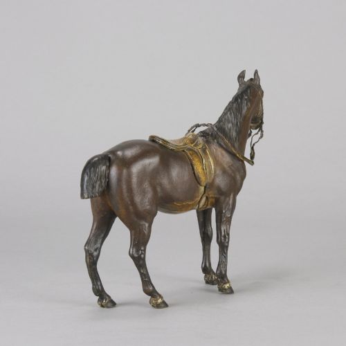 fig 6. A cold-painted bronze sculpture depicting a saddled horse with gold-coloured tack, bridle, and stirrups in a standing pose.