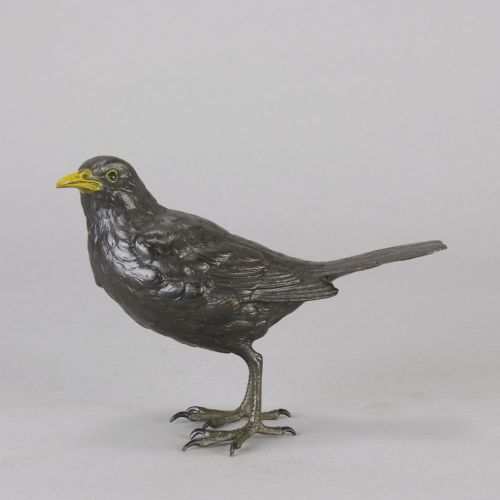 fig 1. An early 20th-century cold-painted bronze figurine depicting a standing blackbird with dark plumage and a bright yellow beak.