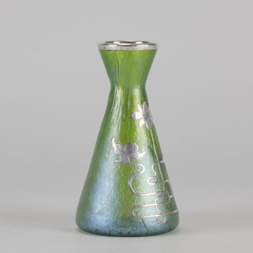 fig 2. A conical iridescent green and blue glass vase decorated with an intricate silver overlay floral design and a silver rim.