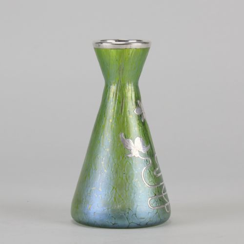 fig 3. A conical iridescent green and blue glass vase decorated with an intricate silver overlay floral design and a silver rim.