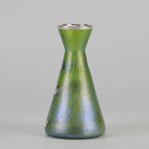 fig 6. A conical iridescent green and blue glass vase decorated with an intricate silver overlay floral design and a silver rim.