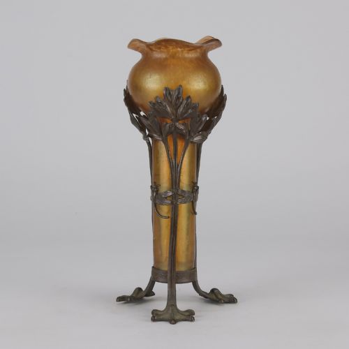 fig 1. An Art Nouveau iridescent amber glass vase supported by a dark patinated bronze mount featuring sculpted leaves and dragonfly motifs on stylised tripod legs.