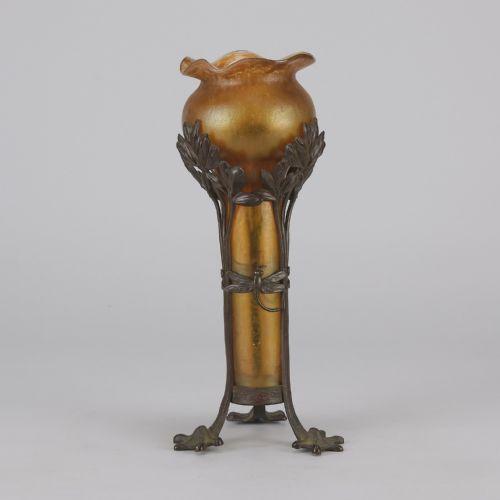 fig 2. An Art Nouveau iridescent amber glass vase supported by a dark patinated bronze mount featuring sculpted leaves and dragonfly motifs on stylised tripod legs.
