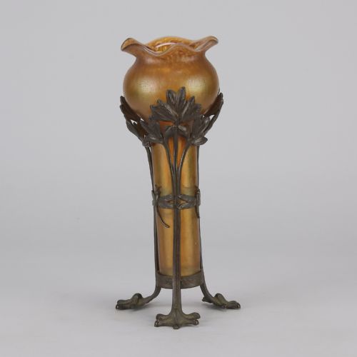 fig 3. An Art Nouveau iridescent amber glass vase supported by a dark patinated bronze mount featuring sculpted leaves and dragonfly motifs on stylised tripod legs.