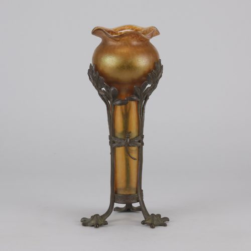 fig 4. An Art Nouveau iridescent amber glass vase supported by a dark patinated bronze mount featuring sculpted leaves and dragonfly motifs on stylised tripod legs.