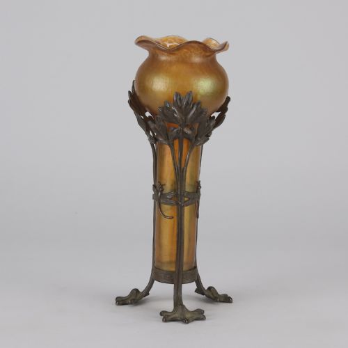 fig 5. An Art Nouveau iridescent amber glass vase supported by a dark patinated bronze mount featuring sculpted leaves and dragonfly motifs on stylised tripod legs.