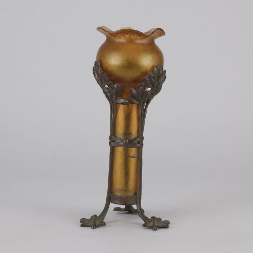 fig 6. An Art Nouveau iridescent amber glass vase supported by a dark patinated bronze mount featuring sculpted leaves and dragonfly motifs on stylised tripod legs.