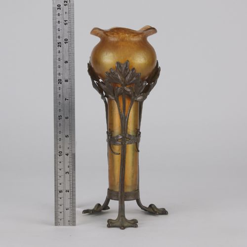 fig 7. An Art Nouveau iridescent amber glass vase supported by a dark patinated bronze mount featuring sculpted leaves and dragonfly motifs on stylised tripod legs.