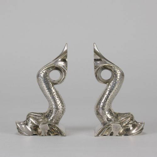 fig 1. A pair of silvered metal bookends sculpted in the shape of upright stylised fish with textured scales and curved tails.