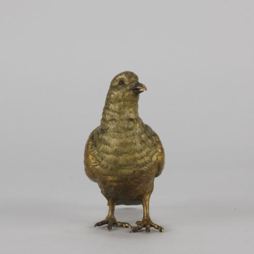 fig 1. A cold-painted bronze figurine depicting a pigeon with textured feathers and a golden finish, standing facing left.