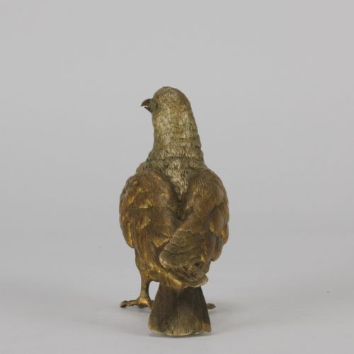 fig 6. A cold-painted bronze figurine depicting a pigeon with textured feathers and a golden finish, standing facing left.