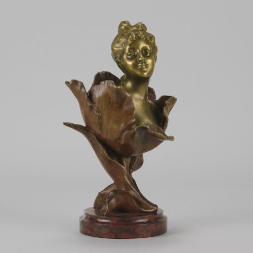fig 2. An Art Nouveau gilt bronze bust depicting a female figure emerging from a stylised floral petal, mounted on a round reddish marble base.