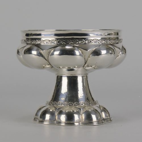 fig 1. An early twentieth-century silver chalice featuring lobed repousse decoration, a wide rim, and a flared pedestal base.