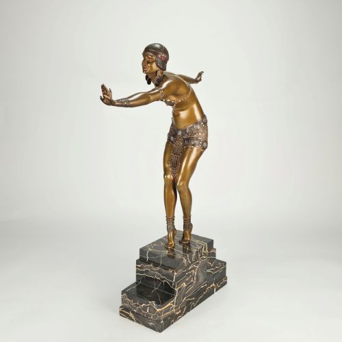 fig 5. An Art Deco gilt bronze sculpture depicting a female dancer in an elaborate costume posed dynamically on a stepped black marbled base.